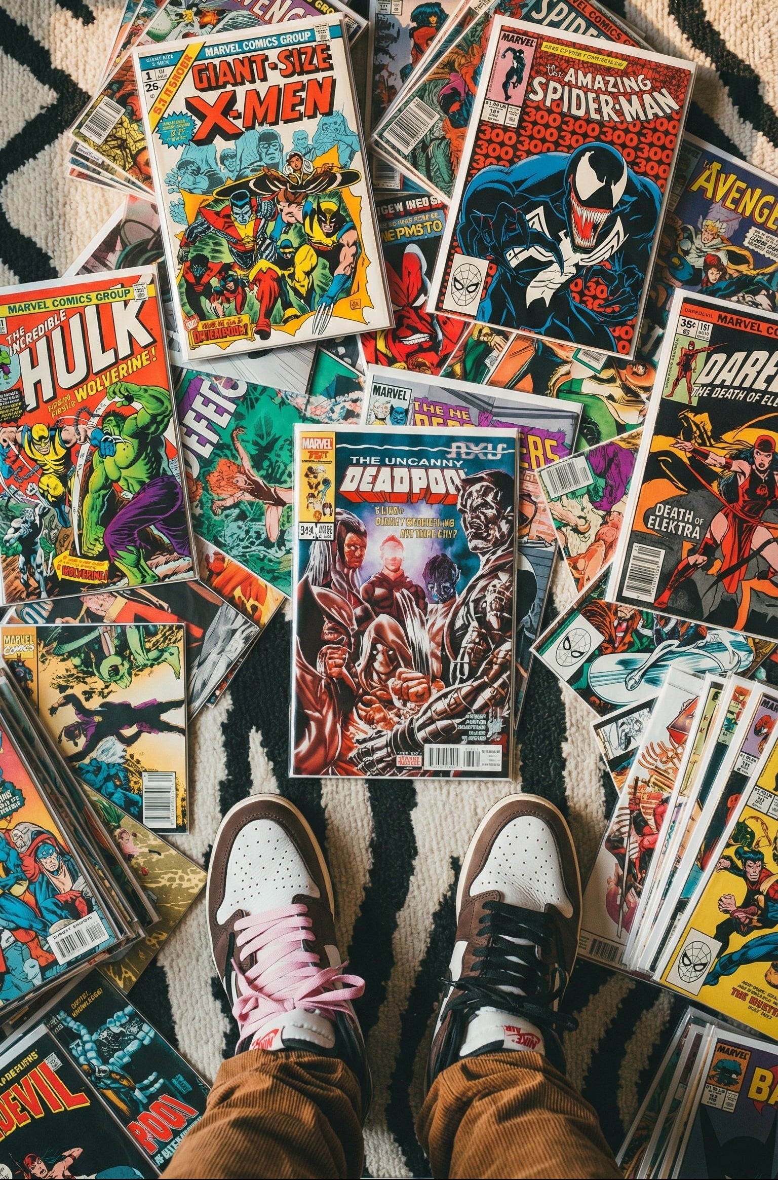 Collection of comic books on a patterned rug with a person's feet visible.
